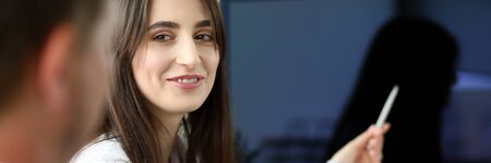 Portrait of pretty businesswoman sitting in modern office and pointing at something on big wide pc...