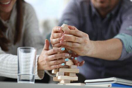 Focus on wooden tabletop board game. Worried people spending quality time with close friend or relative. Warm lovely evening concept. Blurred backgroundの写真素材