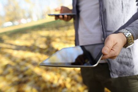 Focus on tablet in male hands. Guy with devices connecting gadgets with each other. Small pc with...