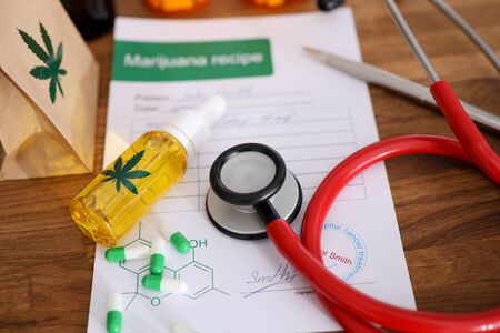 John Smith - fictitious name. Red stethoscope with marijuana recipe on doctor table background closeup. Herbal cancer treatment conceptの写真素材