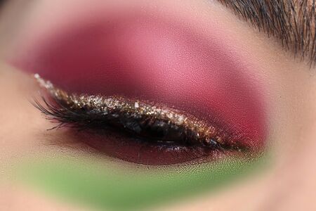 Close-up of magical professional makeup with black lashes smoky eyes and glossy golden eyelid. Pretty woman eye with evening holiday maquillage. Cosmetics and beauty conceptの写真素材