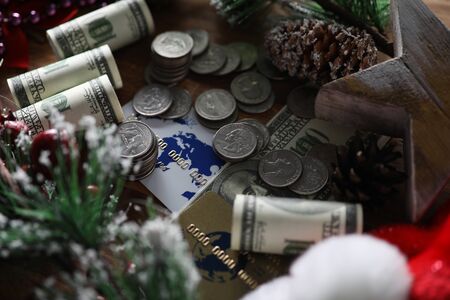 Close-up of coins banknotes and credit cards. Christmas presents and savings. Pinecones and sprig...
