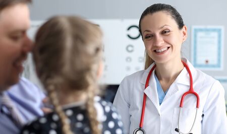 Portrait of smiling ophthalmologist looking at little patient with gladness and joyfulness. Child...
