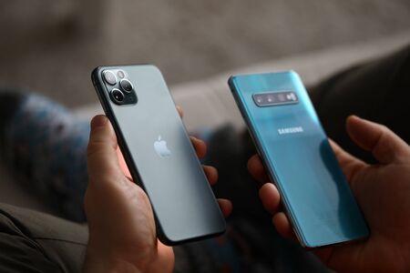 Minsk, Belarus - 11 December 2019 : Male hand hold Apple iphone pro and samsung galaxy s 10....
