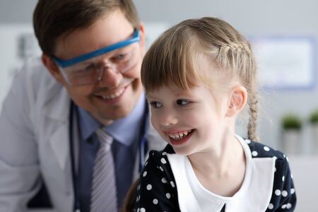 Portrait of happy child with doctor. Man in white medical gown and eyeglasses looking at joyous little patient with joyfulness. Medical and healthcare conceptの写真素材