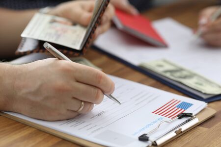 Close-up of person carry information from passport to usa visa application form. Man planning to...