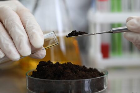 Female chemist in white protective gloves hold test tube against chemistry lab background closeup. Express research crop soil content of beneficial and harmful substances conceptの写真素材