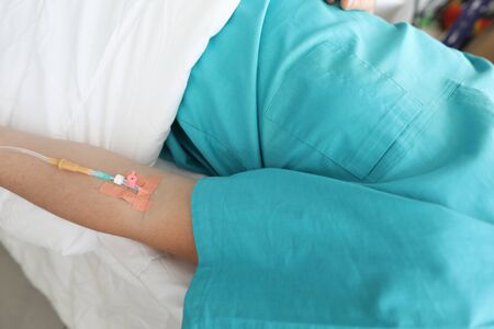 Close-up of peripheral venous catheter in vein of human hand. Medical therapy and aid for person lying in bed of hospital room. Healthcare and medicine conceptの写真素材