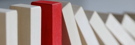 Focus on red object refusing to bend under harsh circumstances affecting other in irreversible sequence of domino effect. One special tile out of many is stopping falling. Strong individual conceptの写真素材