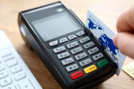 Male hand hold credit card with POS terminal closeup background. Fast payment concept