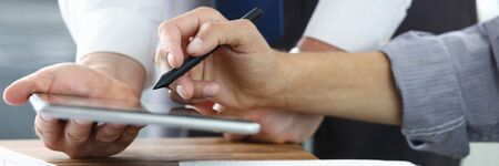 Focus on colleagues hands holding modern tablet and stylos. Businessmen discussion new biz project. Designers creating start-up. Creative work concept. Blurred backgroundの写真素材