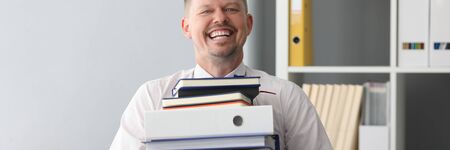 Happy office worker carry huge heavy pile of paper files to work with portrait. Overtime job for for...