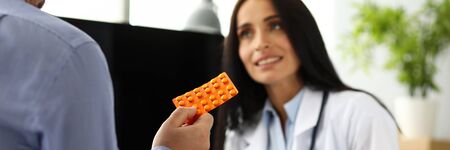 Male visitor holding tablet blister with GP in background close-upの写真素材