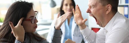 Focus on angry married couple doc appointment in clinic office. Shocked woman showing to screaming...