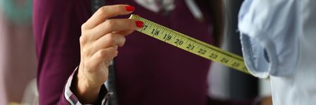 Focus on tender hands of fashioner holding special yellow measuring utility and working on important sewing project with tenderness and calmness. Fashioner conceptの写真素材