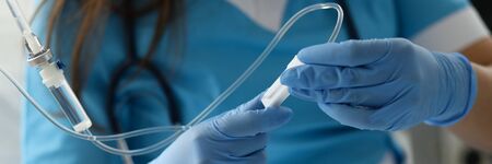 Female nurse hand in blue protective gloves hold dropper against medicine hospital background. Medical education conceptの写真素材