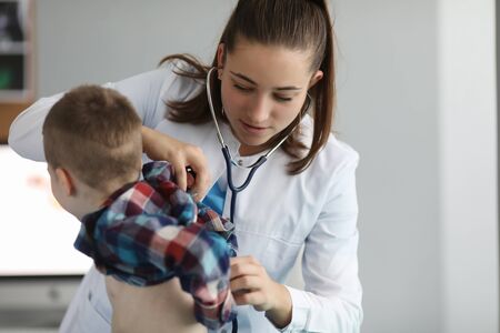 Portrait of smart woman practitioner examining little patient. Pediatrician listening to action of kids heart or breathing with stethoscope. Medicine and healthcare conceptの写真素材