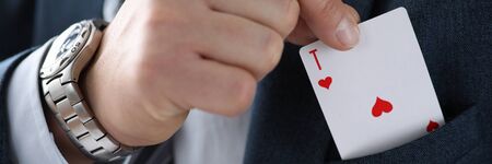 Male businessman hand hold playing card in hand against casino background closeup. Custom solutions...