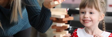 Young mum with little daughter play game in wood block against home background portrait. Happy childhood conceptの写真素材