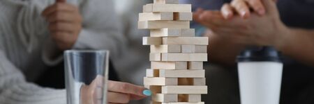 Focus on wooden tabletop game for several players. Happy people spending quality time with close...