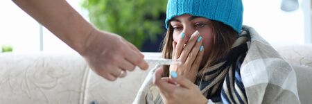 Portrait of poor female suffering from severe flu and covering cute face with tender hand. Girl...