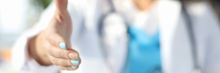 Focus on professional therapist giving hand to patient at hospital. Female doc with stethoscope working in cabinet. Physician welcoming ill person. Medicine and healthcare conceptの写真素材