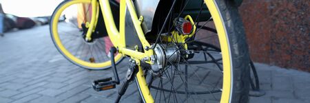 Close-up view of bike parked and secure with locking device on street. Trendy modern yellow bicycle....