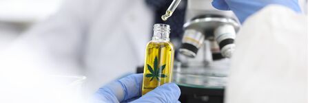 Close-up of persons hand drip blob of cannabinoid oil. Medical worker going to investigate sample...