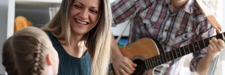 Happy family plays musical instruments on background of new apartment. Credit for good education...