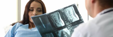 Portrait of beautiful woman discussing important results of x-ray of back with therapist. Lovely...