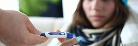 Focus on thermal measuring utility used for curing various sickness from common cold to severe flu. Woman in warm clothes trying to find out body condition. Hard virus conceptの写真素材