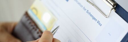 Focus on male hand writing answers to questions in questionnaire of application for schengen visa....
