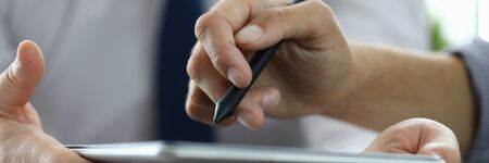 Focus on male hand pointing at screen of modern tablet with stylos. Biz colleagues discussing signing future bargain. Business negotiations concept. Blurred backgroundの写真素材