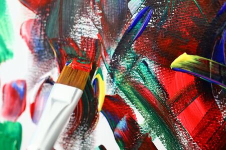 Brush with acrylic paint on background of art canvas closeup