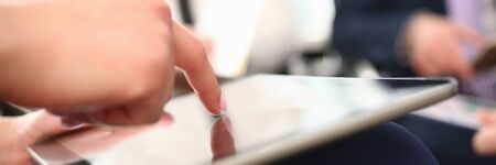 Focus on female finger pointing to something on tablet. Woman explaining details of agreement hard to understand. Young manager showing to boss important information. Company meeting conceptの写真素材