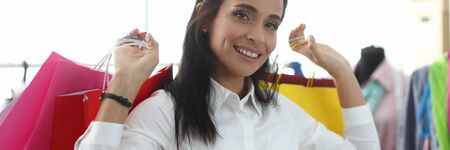 Portrait of woman standing in fashionable clothes shop and looking at camera with happiness and...