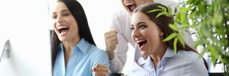 Portrait of beautiful businesspeople holding fists and shouting from happiness. Cheerful colleagues...