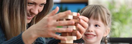 Portrait of preschool child enjoying playing game with smiling mother. Cheerful girl looking at...
