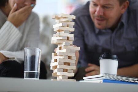 Close-up of wooden tower constructed. Players taking turns removing one brick at time from tower.