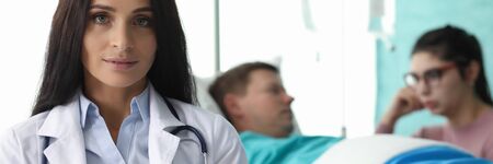 Portrait of young professional doctor in medical gown and stethoscope sitting in hospital room. Selective focus on clinical worker. Healthcare conceptの写真素材