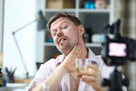 Man filming a video blog about an alcoholic drink. Person is not aware his immoral lifestyle. Rowdy promotes drunkenness. Person is addicted to alcohol. Blogging screaming act in publicの写真素材