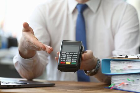Man holds his hand wireless terminal for payment. Bank employee offers to install a wireless...