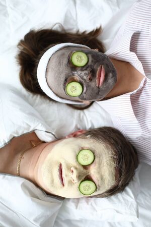 Man and woman put on face mask and cucumbers. Anti-aging masks, it is important to look good everyone, regardless gender and age. Nourishing and anti-aging effect. Clay for cleansing poresの写真素材