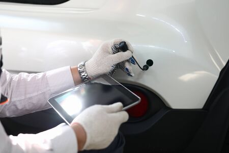Close-up view of professional male mechanic working with digital tablet. Special equipment for...