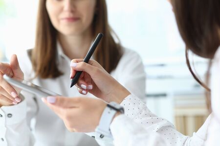 Focus on tender hands of female businesspeople holding important corporate documents and pointing at charts and graphs with writing metallic pen. Accounting office concept. Blurred backgroundの写真素材