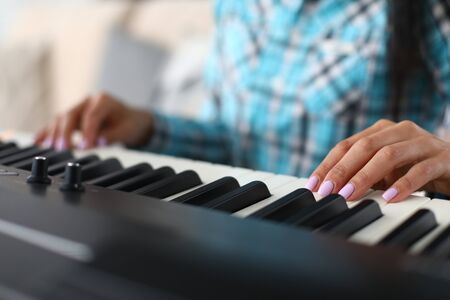Musician fingers on flat keys synthesizer surface. Girl gets used to force pressing to extract sound...