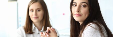 Portrait of smart businesswoman sitting at modern workplace and looking at camera with gladness. Business lady holding tablet and pointing on something. Copy space on screen. Biz meeting conceptの写真素材