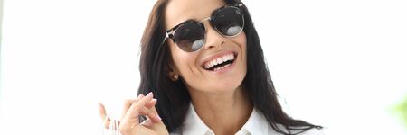 Portrait of joyful female standing and smiling at camera with calmness and happiness and holding...