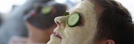 Husband and wife are lying on couch home and doing restoring face masks portrait. Healthy facial skin care at home help conceptの写真素材