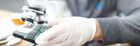 Close-up of gadgets problems fixing with soldering. Man looking at circuit board details through microscope. Technical support service. Worker dealing with electronics maintenance and problemsの写真素材